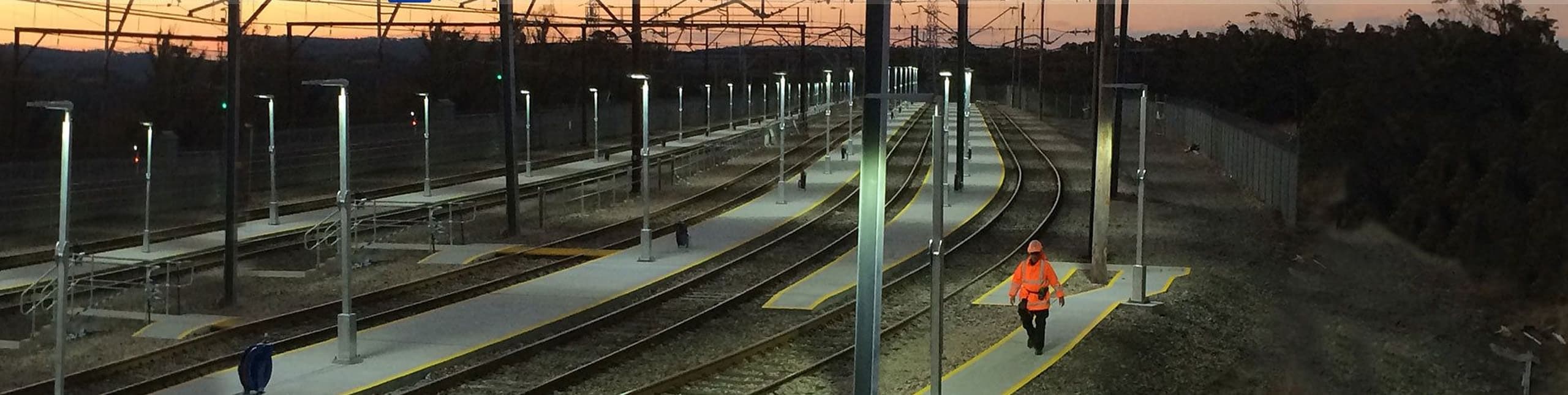 A crew member walking a rail corridor at dusk